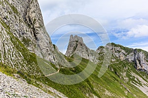 Hikers on the steep path leading to the majestic  Schaefler peak in the  Alpstein mountain range around the Aescher cliff in