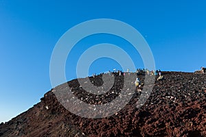 Hikers on Rocky Volcanic Trail Under Clear Blue Sky