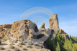 Hikers walk down from the Roque Nublo sacred mountain at Roque Nublo Rural Park, Gran Canary, Canary Islands, Spain