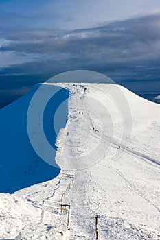 Hikers and walkers on a cold, snow covered mountain in the early morning sunshine Pen-y-Fan