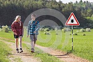 Hikers walking past tick Infected area with danger sign