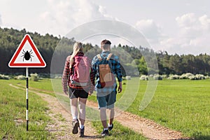 Hikers walking past tick Infected area with danger sign