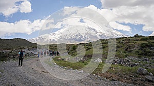 Hikers walking to the basecamp with huge snowy mountain summit in backdrop, Mount Ararat in Turkey