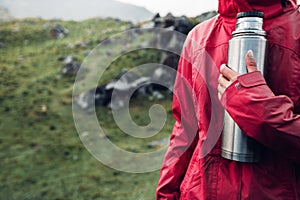 Hiking Adventure Tourism Vacation Holiday Concept. Unrecognizable girl traveler holds a thermos in her hand Overview of a wild la