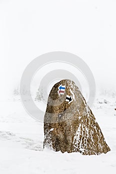 Hiking arrow signs on stone in deep snow, winter inspiring landscape