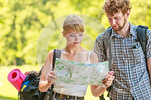 Hiking backpacking couple reading map on trip.