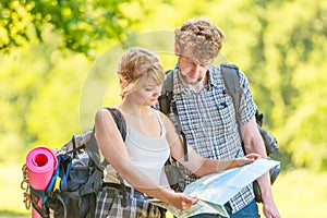 Hiking backpacking couple reading map on trip.