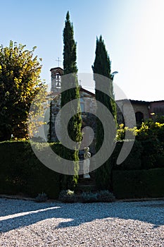 Hiking backroads of Tuscany, resting in shadow of cypress trees at villa entrance, near San Gimignano