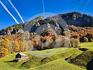 hiking in the beautiful Weisstannen valley. Fall colors in the woods. Alp hut with a view of the mountains