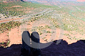 Hiking Boots at the edge of a ledge overlooking a vast expanse of Sedona, Arizona