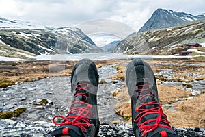 Hiking boots and feet towards icy lake and mountain peaks in Rondane