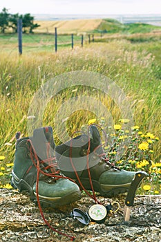 Hiking boots with knife and compass on log in field