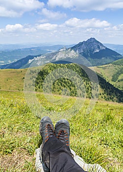 Hiking boots on the legs of the resting tourist with the characteristic peak of Mala Fatra - Velky Rozsutec