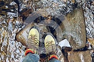 Hiking boots in outdoor action. Top View of Boot on the trail. Close-up Legs In Jeans And sport trekking shoes on rocky