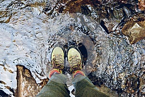 Hiking boots in outdoor action. Top View of Boot on the trail. Close-up Legs In Jeans And sport trekking shoes on rocky