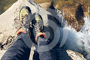 Hiking boots in outdoor action. Top View of Boot on the trail. Close-up Legs In Jeans And sport trekking shoes on rocky srones of