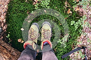 Hiking boots in outdoor action. Top View of Boot on the trail. Close-up Legs In Jeans And sport trekking shoes on rocky srones of