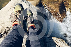 Hiking boots in outdoor action. Top View of Boot on the trail. Close-up Legs In Jeans And sport trekking shoes on rocky srones of