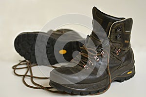 Old weathered natural leather hiking boots isolated on white background.