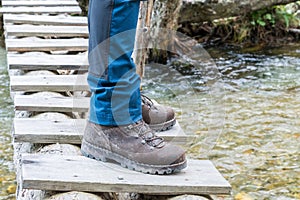 Hiking boots on tree trunk bridge over a creek