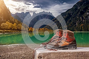 Hiking boots on wooden bench at Landro lake in the Dolomites mountains in Italy. Italian landscape or scenery.