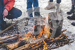 hiking bowlers over the fire in the forest in winter