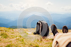 Hiking in Carpathian mountains. Hiker man resting by backpack enjoying landscape. Traveling in summer Ukraine