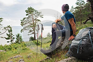 Hiking climbing cliff adventure. Backpacker man resting after hiking looking at beautiful view. Hiker with backpack sits