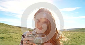 Hiking, countryside and face with woman, camera and nature with sunshine and wind. Person, travel photographer and girl