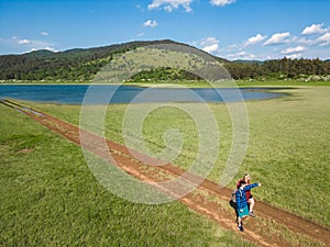 Hiking couple enjoy walking along a trail near blue mountain lake, aerial view