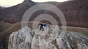 Hiking couple relaxing on a mountain peak. Aerial slow motion view