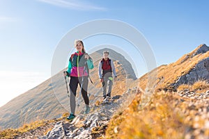 Hiking couple walking up mountain ridge on a sunny autumn day