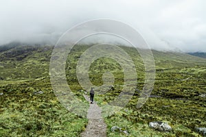 Hiking through dramatic and cloudy landscape  of Buachaille Etive Beag in the Scottish Highlands