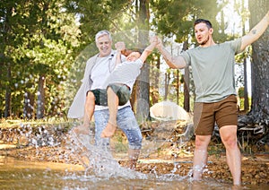 Hiking, grandfather and dad swinging a boy with a water splash in the forest while on a camping trip together. Children