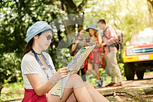 Hiking - hikers looking at map. Couple or friends navigating together smiling happy during camping travel hike outdoors in forest.