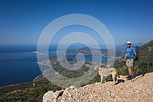 Hiking Lycian way. Man tourist and dog stand on path over Mediterranean sea coast on Lycian Way trail