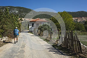 Hiking Lycian way. Man is trekking through Bezirgan village on Lycian Way trail along old broken ragged fence