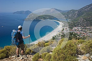 Hiking on Lycian way trail. Man with backpack enjoy view of Oludeniz beach and Blue Lagoon from Lycian Way trail