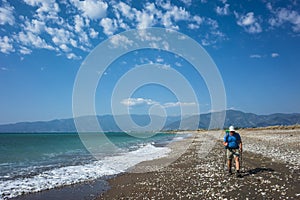 Hiking on Lycian way trail. Man with backpack trekking along long Finike beach, Mediterranean coast of Turkey