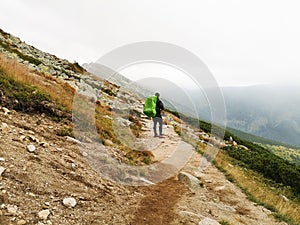 Hiking man with backpack standing enjoying mountains scenery