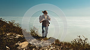 Hiking Man climbing to the top and looks to the side of the clouds. Motivation, travel, search, scout, wanderlust, tourism concept