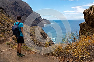 Hiking man with scenic view of coastline of Anaga mountain range on Tenerife, Canary Islands, Spain. View on Cabezo el Tablero photo