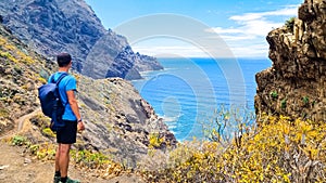 Hiking man with scenic view of coastline of Anaga mountain range on Tenerife, Canary Islands, Spain. View on Cabezo el Tablero photo