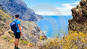 Hiking man with scenic view of coastline of Anaga mountain range on Tenerife, Canary Islands, Spain. View on Cabezo el Tablero