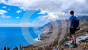 Hiking man with scenic view of coastline of Anaga mountain range on Tenerife, Canary Islands, Spain. View on Roque de las Animas