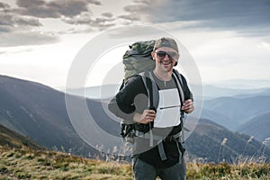 Hiking man or trail runner in mountains, inspirational landscape. Motivated hiker with backpack looking at mountain view