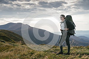 Hiking man or trail runner in mountains, inspirational landscape. Motivated hiker with backpack looking at mountain view