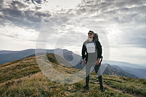 Hiking man or trail runner in mountains, inspirational landscape. Motivated hiker with backpack looking at mountain view