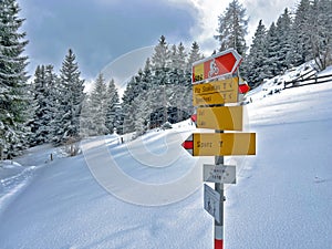 Hiking markings and orientation signs with signposts for navigating in the idyllic winter ambience above the tourist resort