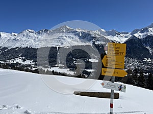 Hiking markings and orientation signs with signposts for navigating in the idyllic winter ambience of the Swiss Alps